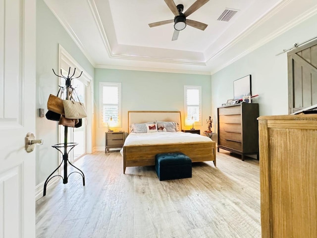 bedroom featuring a tray ceiling, multiple windows, light wood-type flooring, and ceiling fan