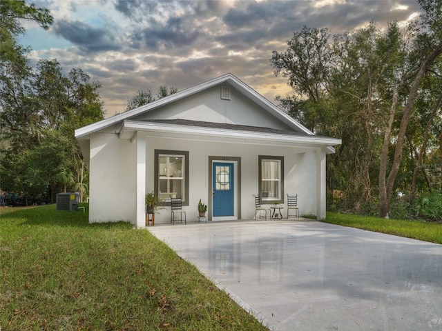 view of front of home featuring a porch, central AC, and a lawn