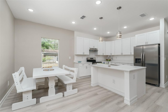 kitchen with stainless steel appliances, pendant lighting, a center island with sink, and white cabinets