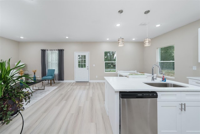 kitchen featuring white cabinets, stainless steel dishwasher, pendant lighting, light hardwood / wood-style floors, and sink