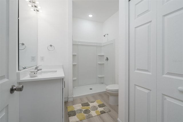 bathroom featuring toilet, hardwood / wood-style flooring, vanity, and a shower