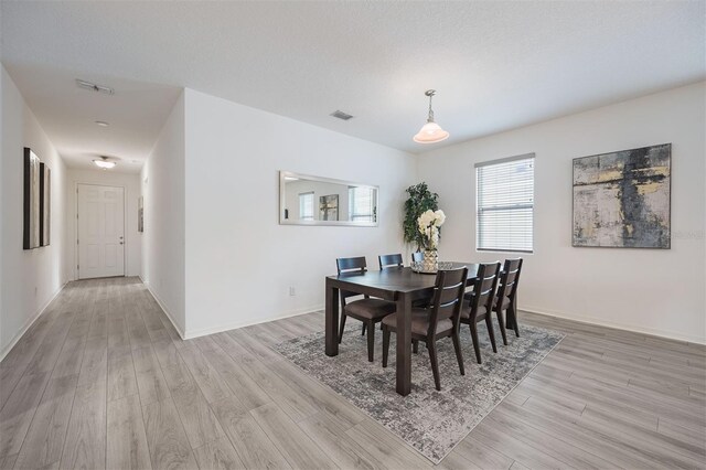 dining space featuring a textured ceiling and light hardwood / wood-style flooring