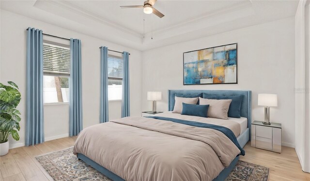 bedroom featuring ornamental molding, ceiling fan, light hardwood / wood-style floors, and a raised ceiling