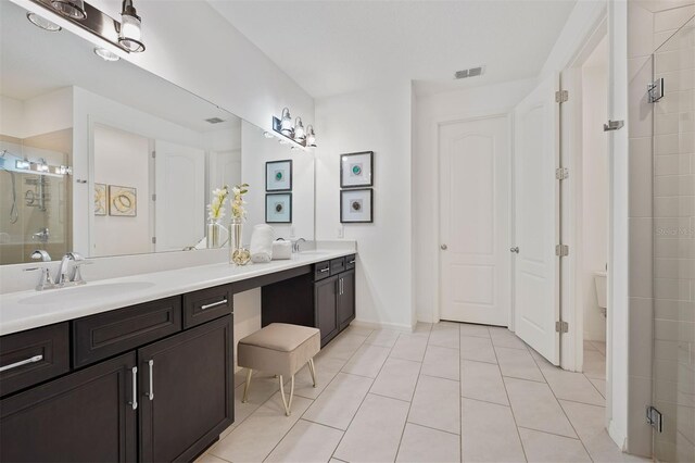 bathroom featuring toilet, an enclosed shower, vanity, and tile patterned floors