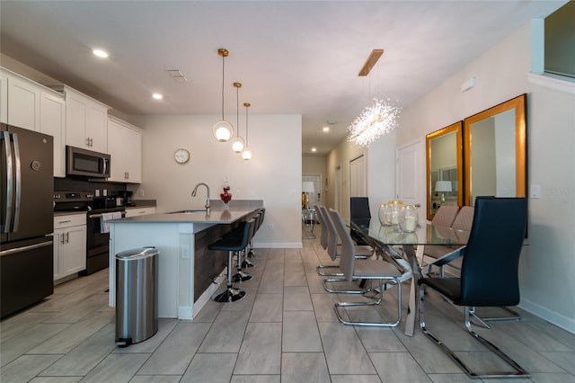 kitchen featuring appliances with stainless steel finishes, a kitchen island with sink, sink, and pendant lighting