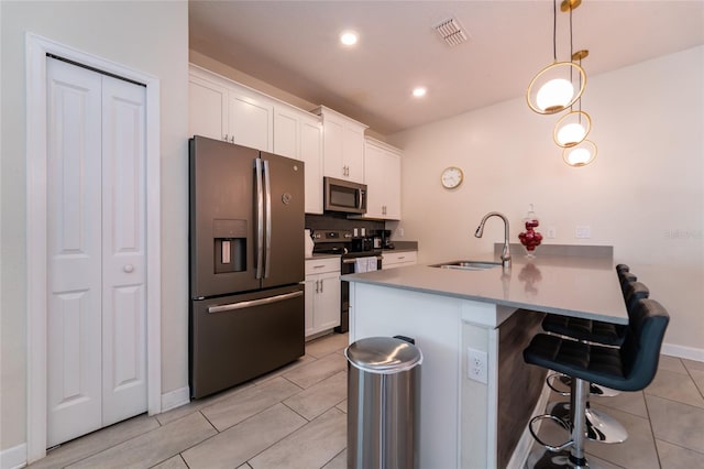 kitchen with appliances with stainless steel finishes, sink, hanging light fixtures, a kitchen breakfast bar, and white cabinets