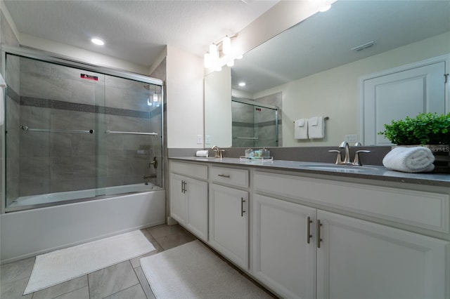 bathroom with vanity, enclosed tub / shower combo, a textured ceiling, and tile patterned floors