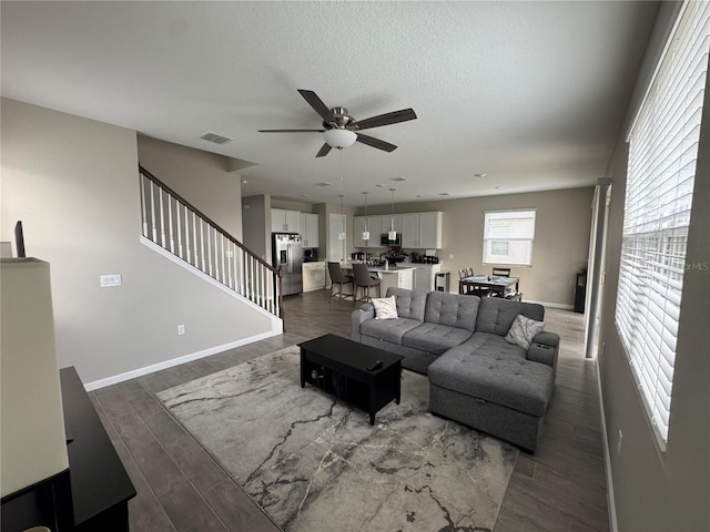 living room with ceiling fan, a textured ceiling, and dark hardwood / wood-style flooring