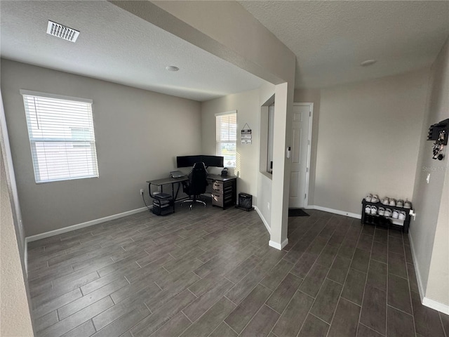 unfurnished office featuring a healthy amount of sunlight, a textured ceiling, and dark hardwood / wood-style floors