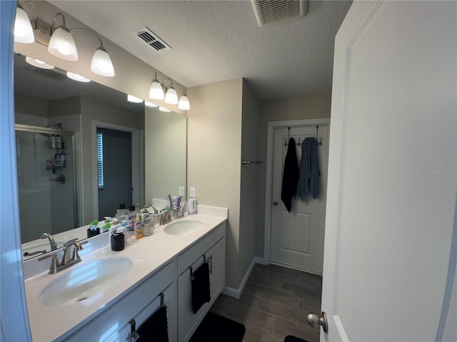 bathroom with vanity, a textured ceiling, and an enclosed shower