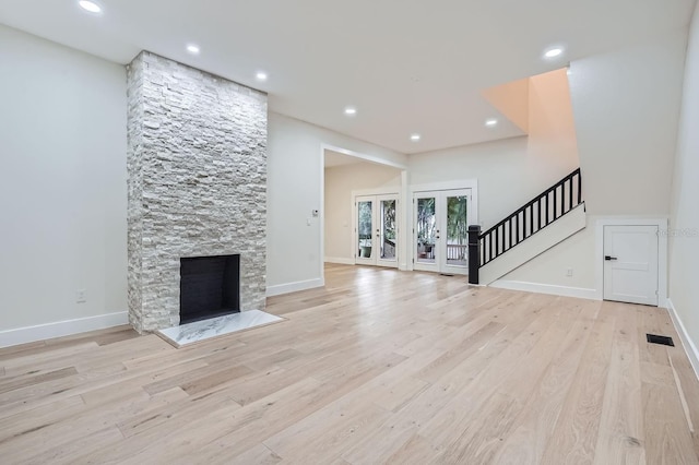 unfurnished living room featuring a stone fireplace and light hardwood / wood-style flooring