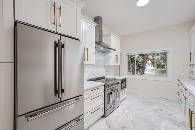 734 S Mills Ave, Orlando, FL 32801 - kitchen featuring decorative backsplash, marble finish floor, wall chimney range hood, white cabinetry, and premium appliances