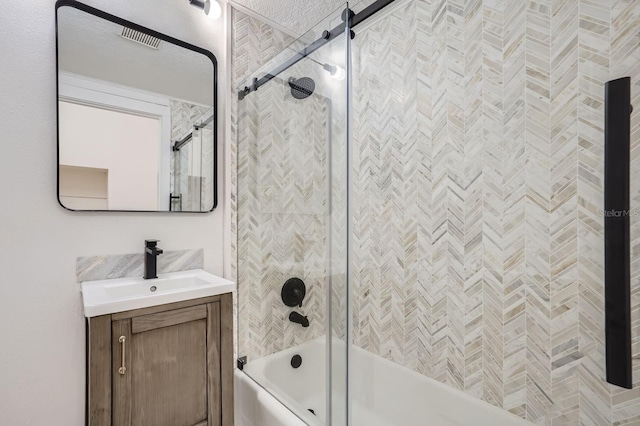 bathroom with vanity, combined bath / shower with glass door, and a textured ceiling