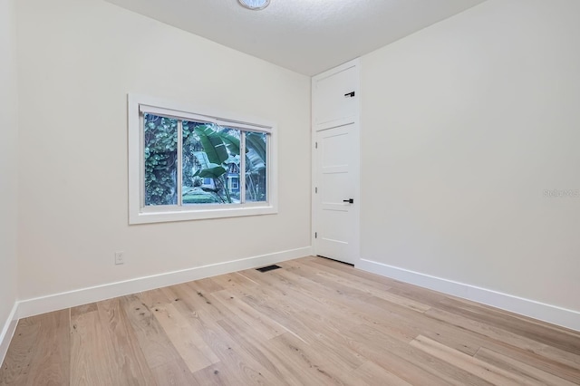 spare room featuring a textured ceiling and light hardwood / wood-style floors