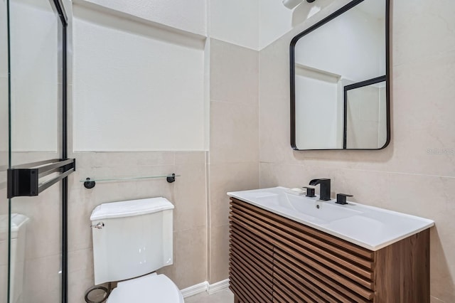 bathroom with vanity, tile walls, and toilet