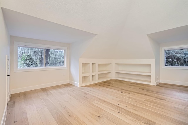 bonus room with built in features, a textured ceiling, light hardwood / wood-style flooring, and lofted ceiling