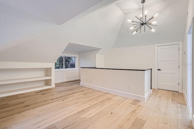 additional living space with light hardwood / wood-style floors, lofted ceiling, and a notable chandelier