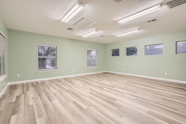 unfurnished room featuring light hardwood / wood-style floors and a textured ceiling