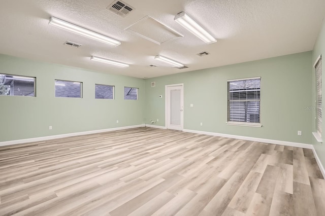 unfurnished room with light hardwood / wood-style flooring and a textured ceiling