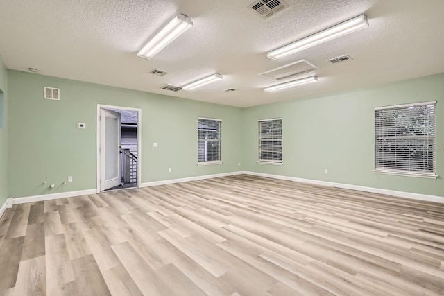 empty room featuring a textured ceiling and light hardwood / wood-style flooring