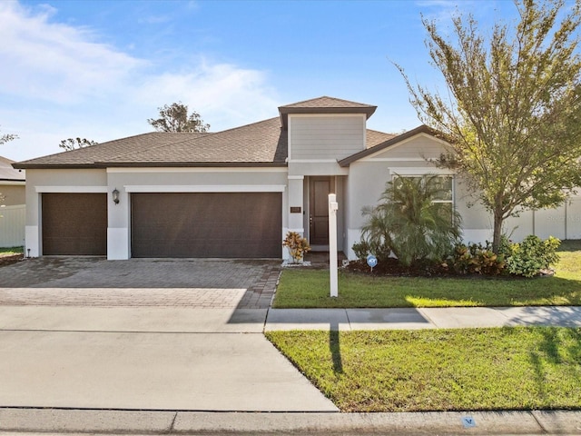 528 Bellissimo Pl, Howey In The Hills, FL 34737 - prairie-style home with an attached garage, stucco siding, a front lawn, decorative driveway, and roof with shingles