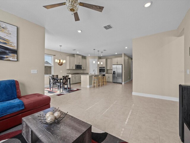528 Bellissimo Pl, Howey In The Hills, FL 34737 - living area featuring recessed lighting, baseboards, visible vents, light tile patterned flooring, and ceiling fan with notable chandelier