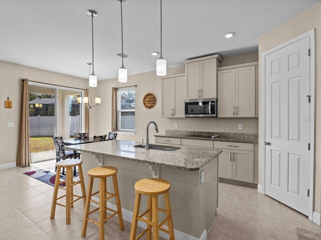 528 Bellissimo Pl, Howey In The Hills, FL 34737 - kitchen with light tile patterned floors, a sink, a center island with sink, stainless steel microwave, and black electric cooktop