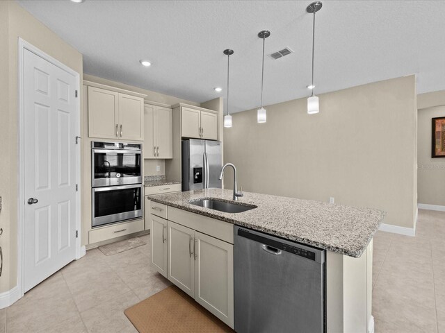 528 Bellissimo Pl, Howey In The Hills, FL 34737 - kitchen featuring light stone countertops, light tile patterned flooring, a sink, a center island with sink, and appliances with stainless steel finishes