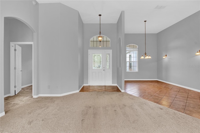 foyer featuring carpet flooring, a towering ceiling, and a notable chandelier