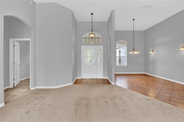 4538 Nottoway Dr, Leesburg, FL 34748 - carpeted foyer with tile patterned flooring, a towering ceiling, baseboards, arched walkways, and a chandelier