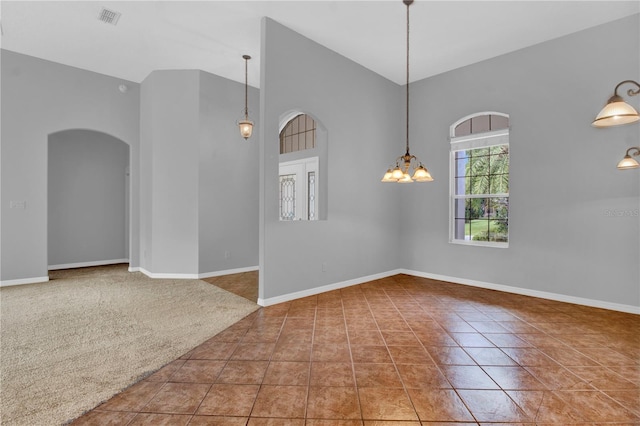 tiled spare room with a chandelier and high vaulted ceiling