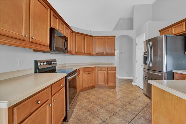 kitchen featuring stainless steel appliances, light tile patterned floors, and vaulted ceiling