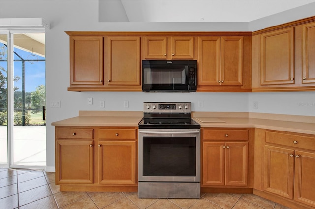 kitchen featuring stainless steel electric range, lofted ceiling, and light tile patterned floors