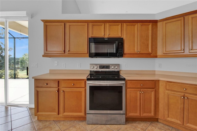 4538 Nottoway Dr, Leesburg, FL 34748 - kitchen with brown cabinets, light countertops, stainless steel electric range oven, light tile patterned flooring, and black microwave