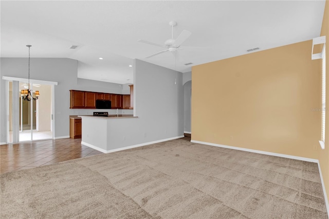 unfurnished living room with ceiling fan with notable chandelier, carpet floors, sink, and lofted ceiling