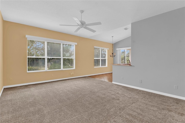 carpeted spare room featuring lofted ceiling and ceiling fan with notable chandelier