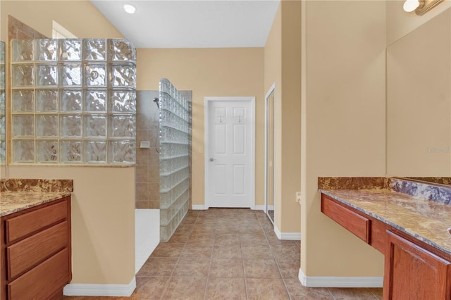 bathroom with tile patterned flooring, vanity, and a tile shower