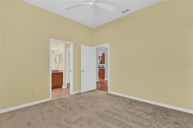 unfurnished bedroom with ensuite bathroom, light colored carpet, and ceiling fan