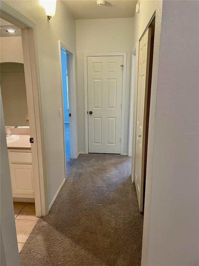 hall featuring light carpet and sink