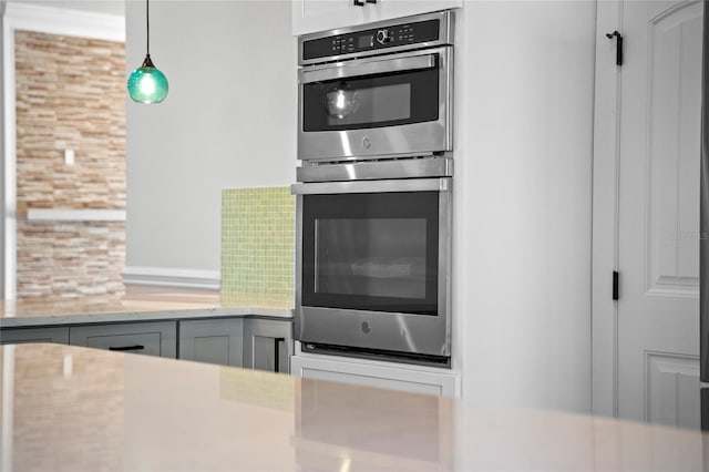 kitchen featuring white cabinetry, decorative light fixtures, decorative backsplash, and double oven