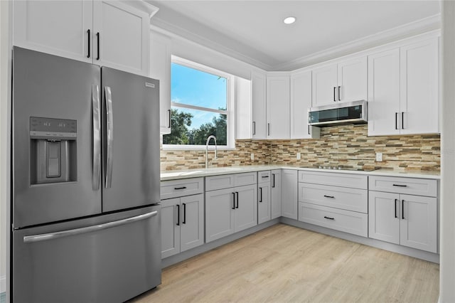 kitchen featuring stainless steel appliances, sink, backsplash, light hardwood / wood-style flooring, and white cabinets