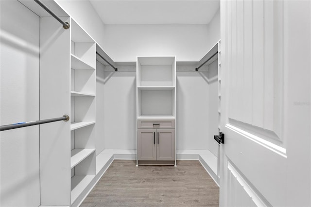 walk in closet with light hardwood / wood-style floors