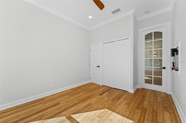 unfurnished bedroom with ornamental molding, a closet, hardwood / wood-style floors, and ceiling fan