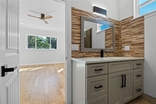 bathroom with ornamental molding, backsplash, vanity, hardwood / wood-style flooring, and ceiling fan