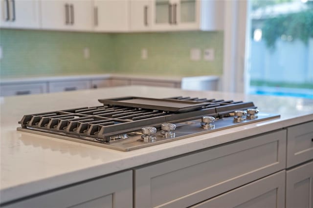 interior details featuring white cabinets, stainless steel gas stovetop, and tasteful backsplash