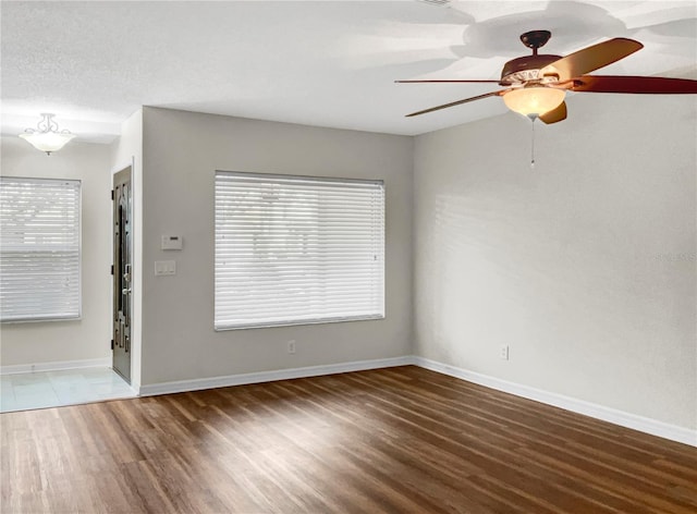 empty room with a textured ceiling, dark wood-type flooring, and ceiling fan