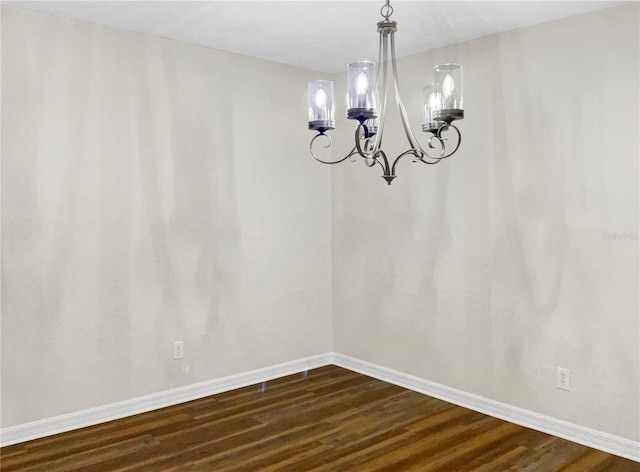 unfurnished dining area with dark wood-type flooring and an inviting chandelier