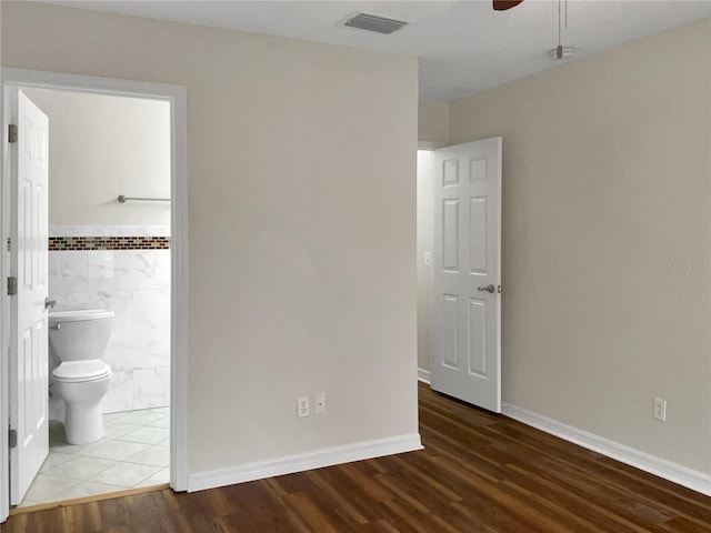 unfurnished bedroom with ceiling fan, ensuite bathroom, and hardwood / wood-style floors