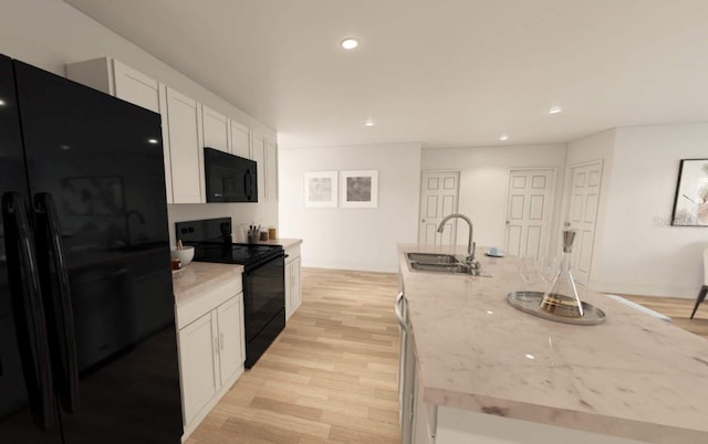 kitchen with white cabinets, light stone countertops, light hardwood / wood-style flooring, black appliances, and sink