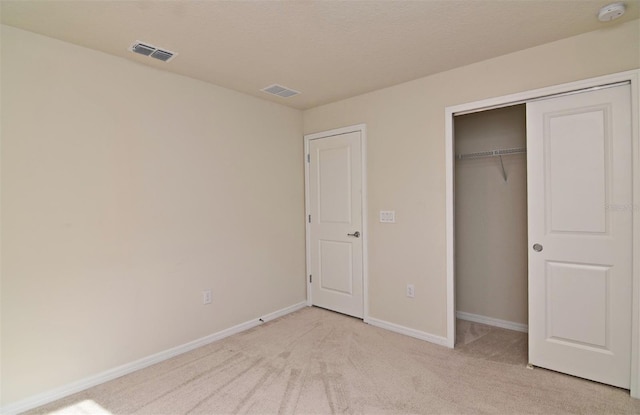 unfurnished bedroom featuring light colored carpet and a closet